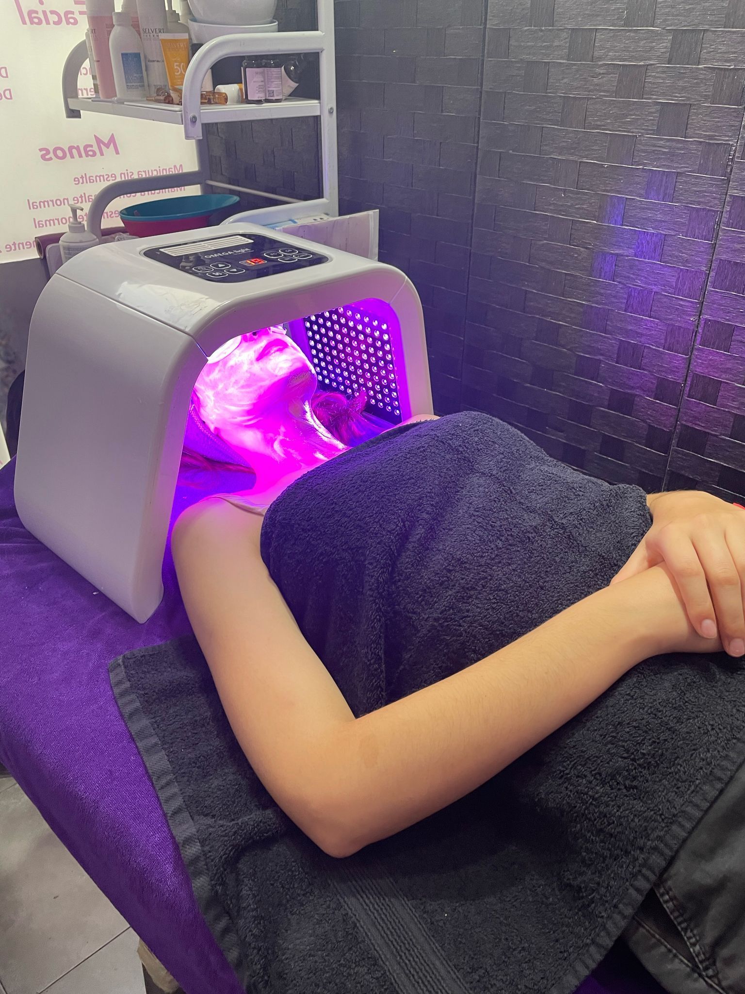 Una mujer está acostada en una cama con una luz violeta en su cara.