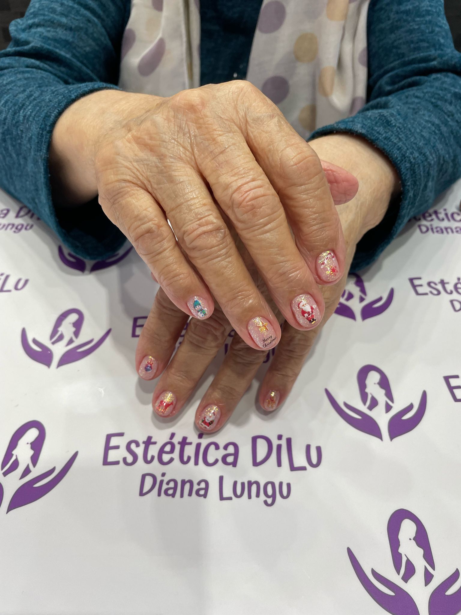 Una mujer está sentada en una mesa con las manos juntas frente a un cartel que dice estetica dilu diana lungu