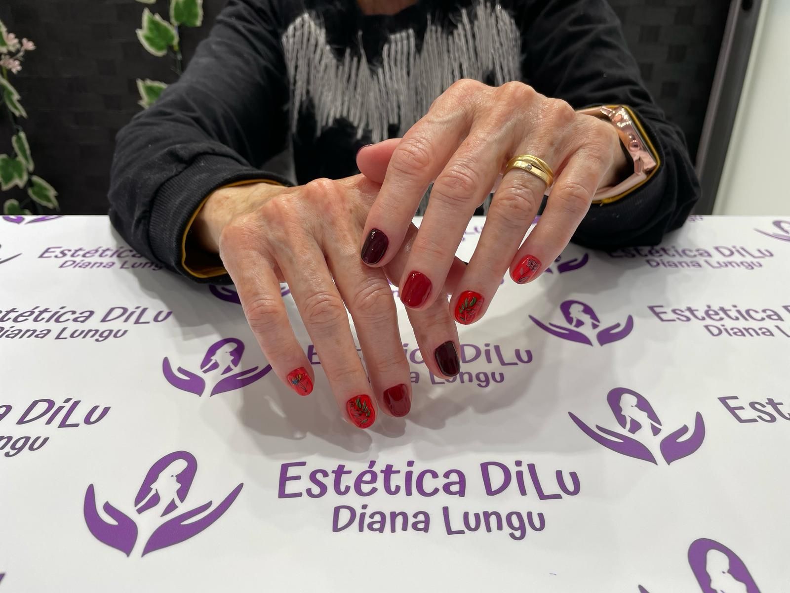 Una mujer está sentada en una mesa con uñas rojas y un anillo en el dedo.