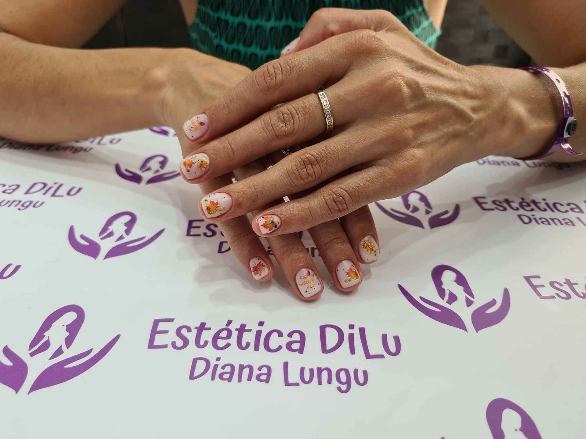 Una mujer está sentada en una mesa con las manos juntas frente a un cartel que dice estetica dilu diana lungu