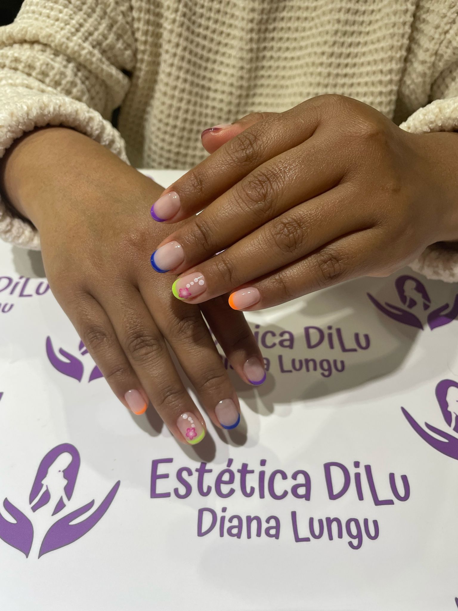 Las uñas de una mujer se exhiben frente a un cartel que dice Estetica Dilu Diana Lungu.