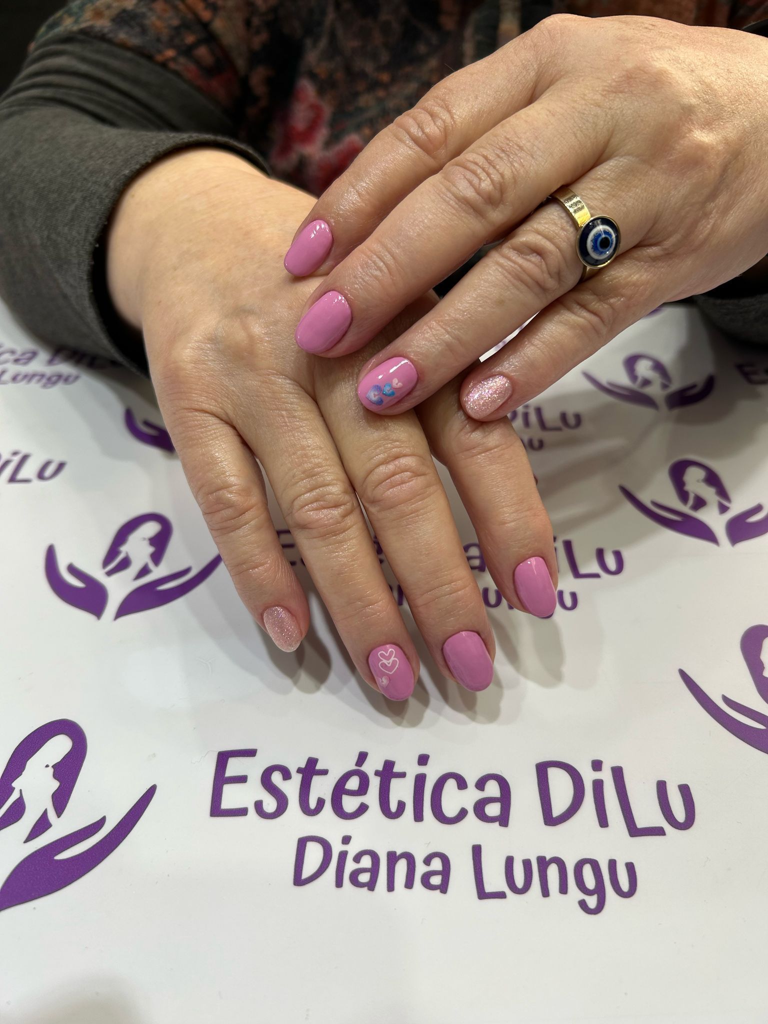 Las uñas de una mujer están pintadas de rosa y lleva un anillo.