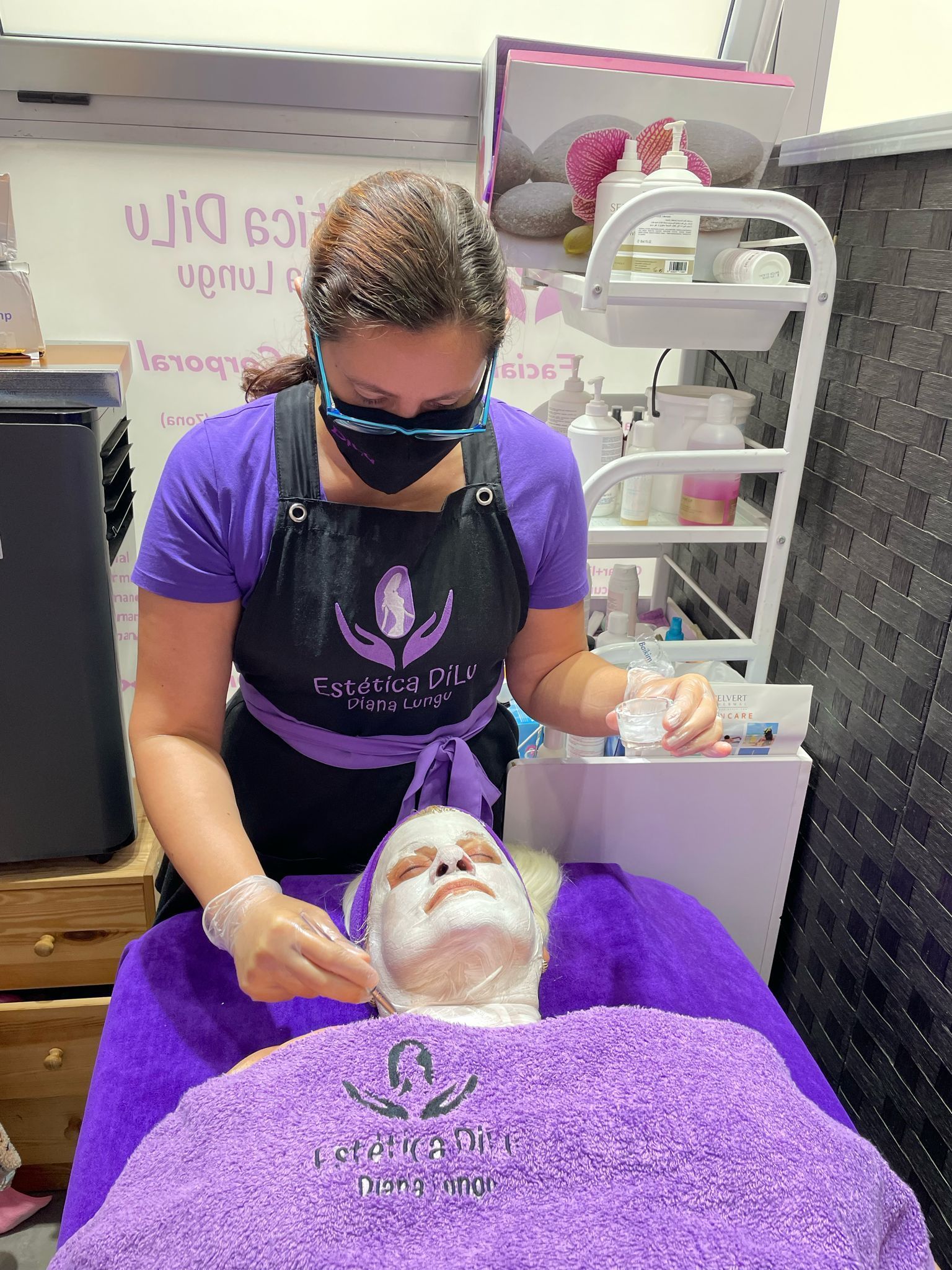 Una mujer que lleva una máscara está aplicando una máscara en la cara de una mujer.