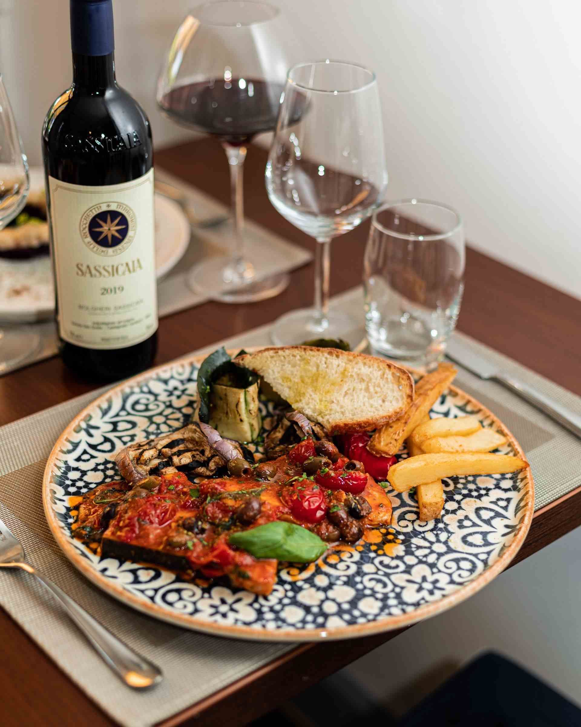 Assiette de nourriture avec bouteille de vin et verres sur une table.