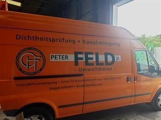 Ein orangefarbener Lieferwagen mit der Aufschrift „Peter Feld“ an der Seite steht in einer Garage.