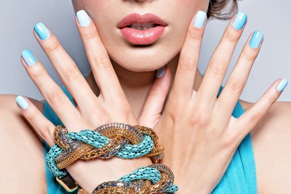 Una mujer con uñas azules y una pulsera en la muñeca.