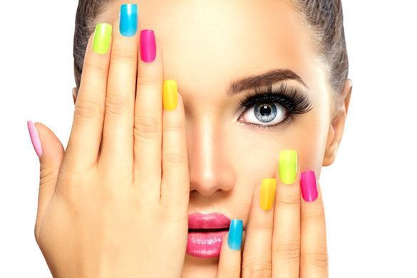 Una mujer con uñas de colores se cubre la cara con las manos.