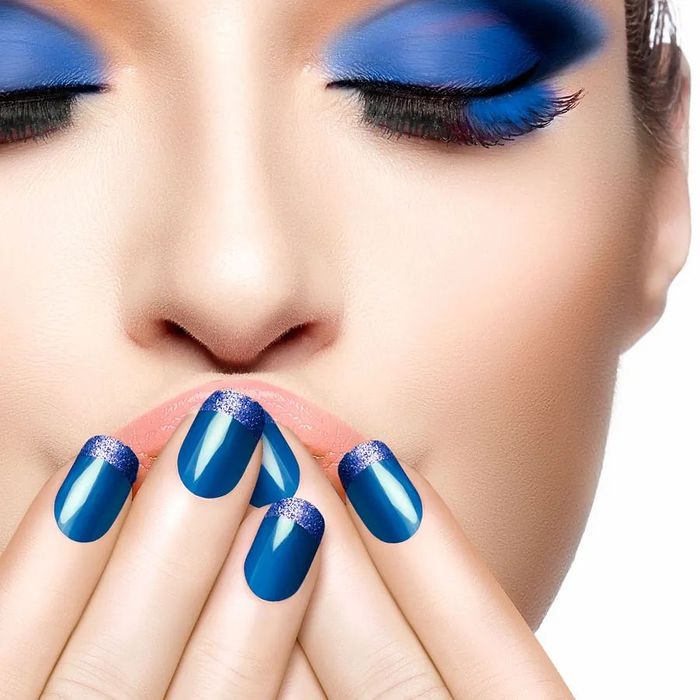 Un primer plano del rostro de una mujer con uñas azules.