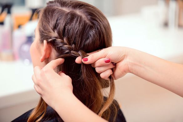 Una mujer se está trenzando el cabello en una peluquería.