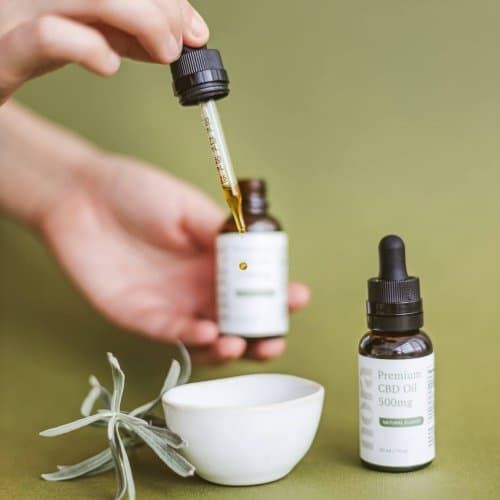 Une personne verse une goutte d'huile de CBD dans un bol.