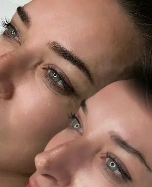 Dos caras con cejas oscuras y delineador de ojos, piel clara, primer plano.