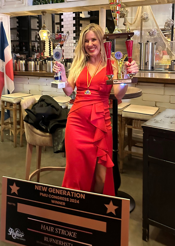 Mujer con vestido rojo, sonriendo, sosteniendo trofeos en un restaurante. Cartel del evento en primer plano.