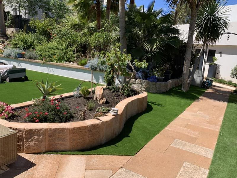 Un exuberante jardín verde con una pasarela que conduce a una casa.