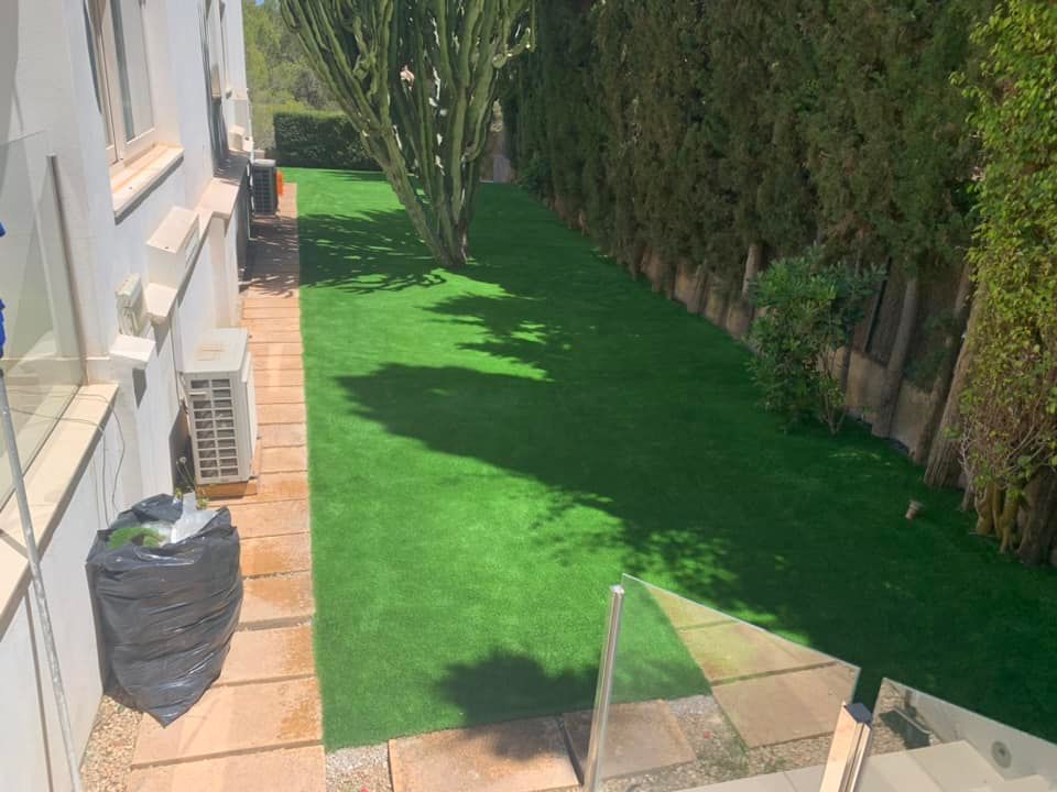 Un exuberante césped verde está rodeado de árboles y un edificio blanco.