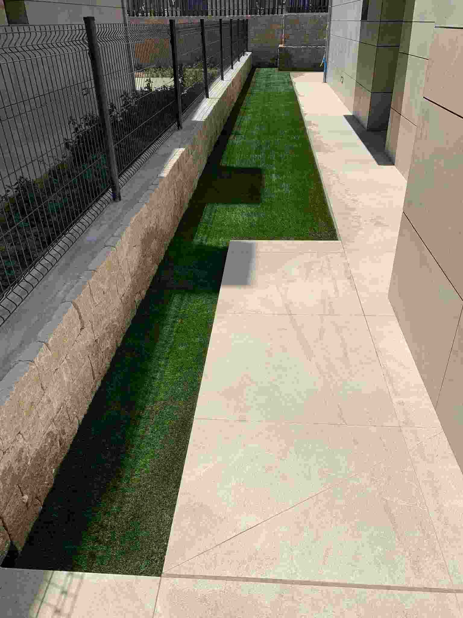 Una pasarela que conduce a una zona de césped con una valla al fondo.