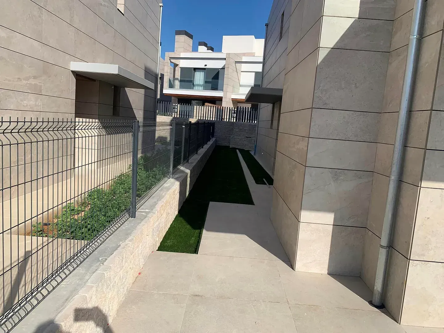 Una pasarela entre dos edificios con una valla al fondo.