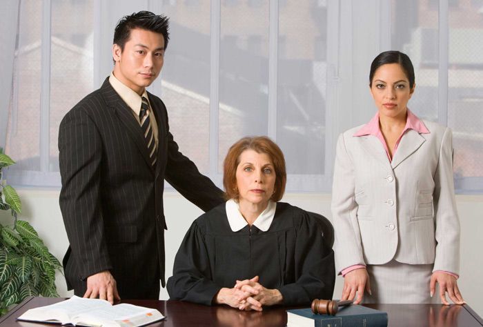 Un grupo de abogados está de pie alrededor de un juez sentado en un escritorio.