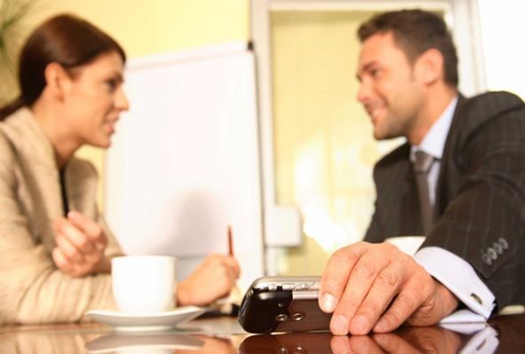 Un hombre y una mujer están sentados en una mesa con una taza de café.