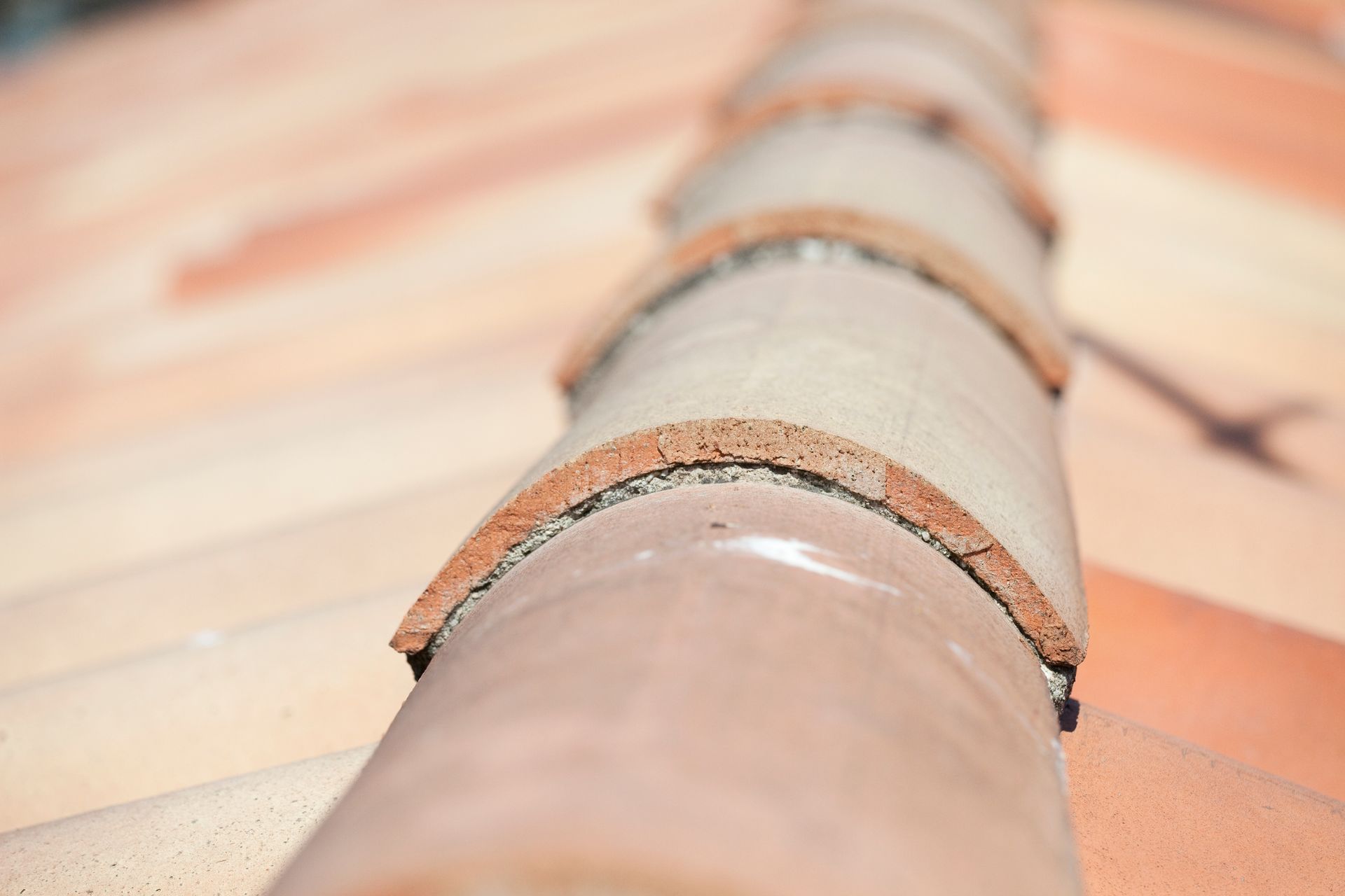 Gros plan d'un toit en tuiles en terre cuite, montrant des tuiles faîtières.