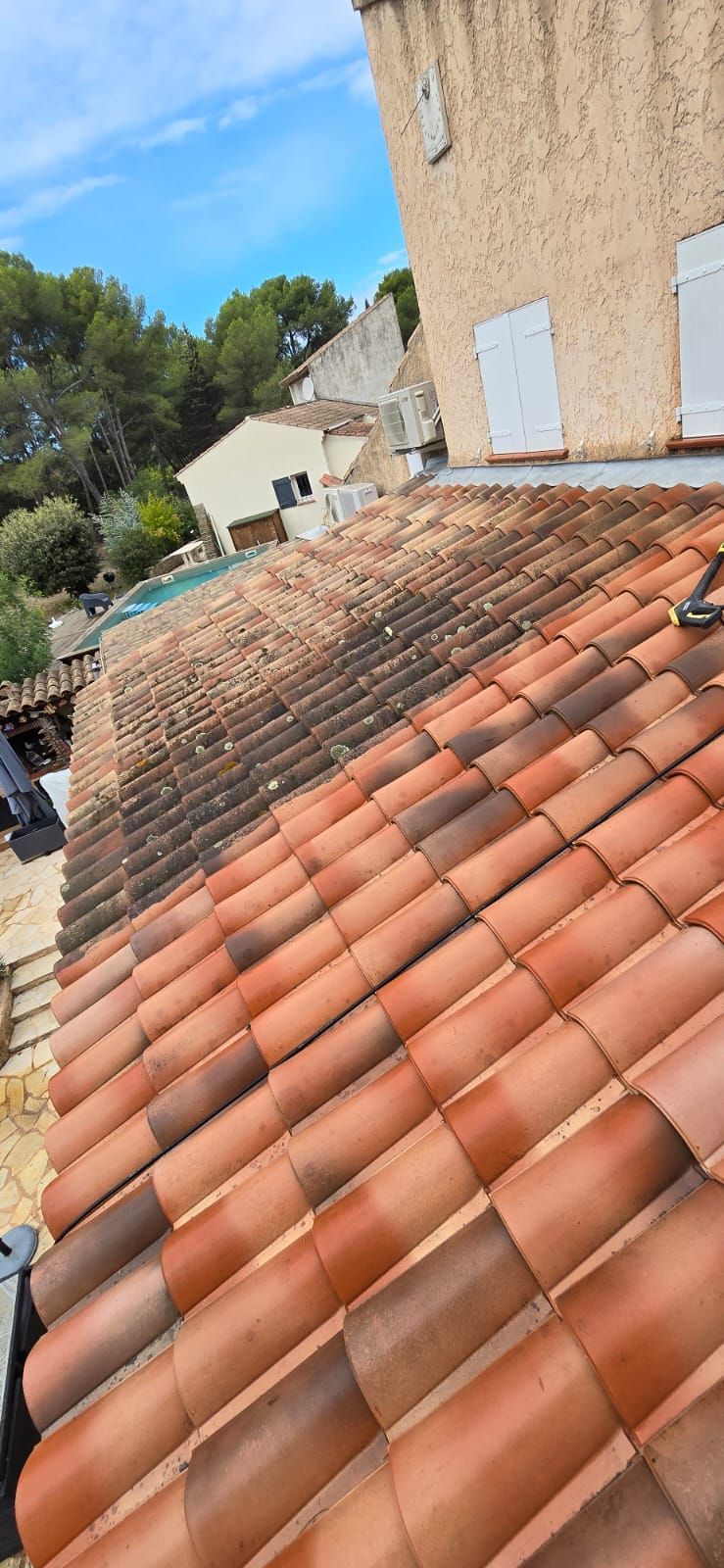 Toit en tuiles d'argile rouge avec des taches sombres.