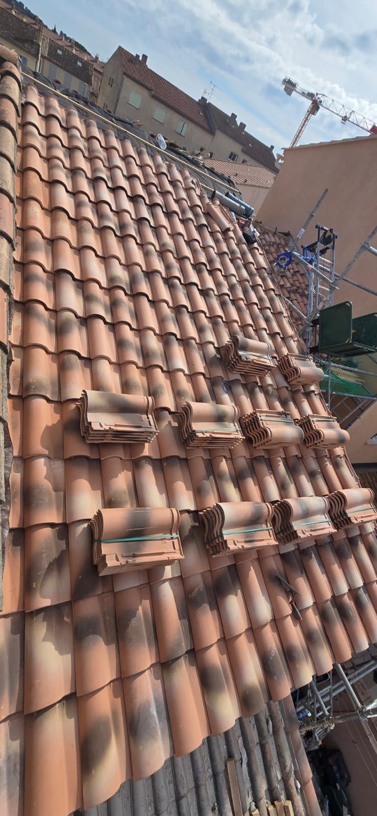 Gros plan d'un toit de tuiles rouges avec quelques tuiles empilées dessus.