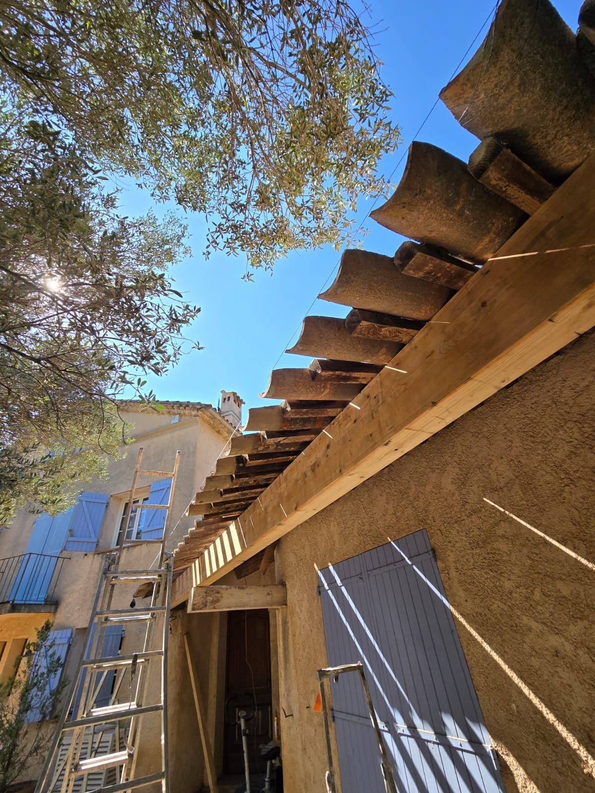 Maison en construction avec des tuiles partiellement posées.