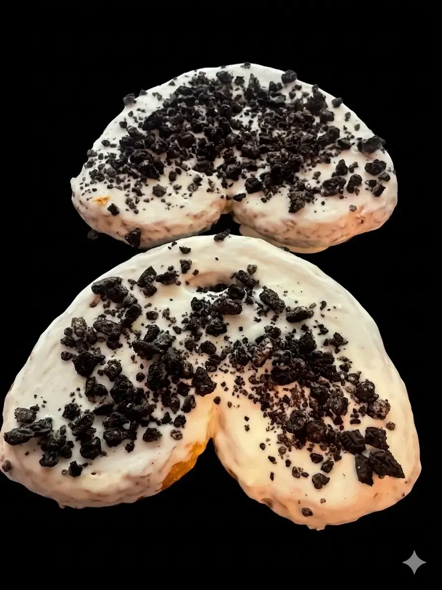 Dos pasteles de media luna cubiertos con migas sobre un fondo negro.