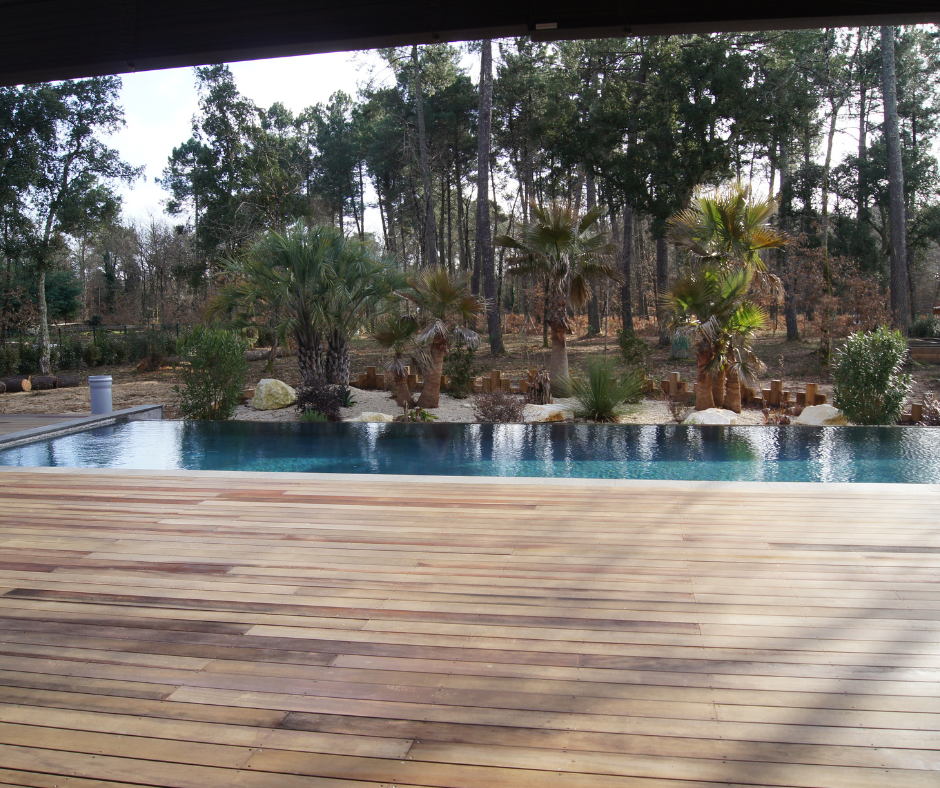 Une terrasse en bois surplombe une piscine et un paysage luxuriant arboré.