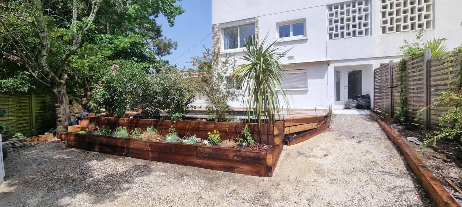 Bac de fleurs surélevé en bois devant une résidence à Pyla-sur-Mer.