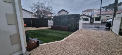 Allée de maison avec du gravier et portail ouvert.