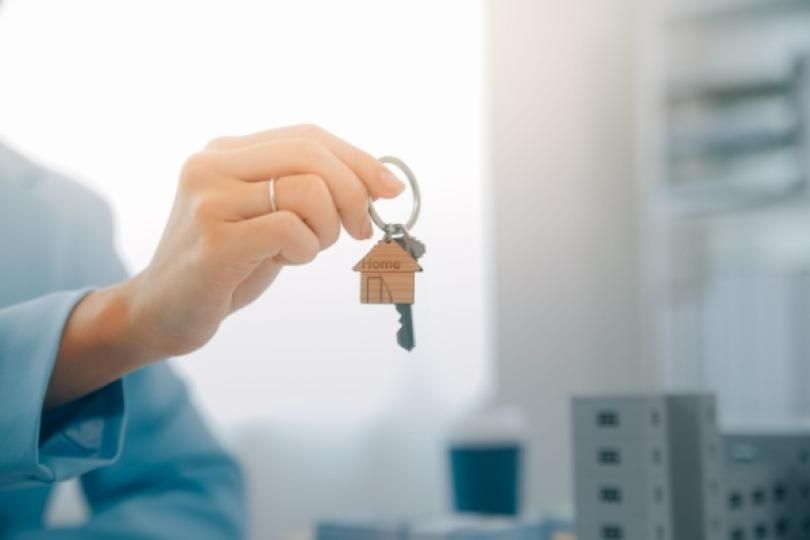 Une femme tenant un porte-clés avec une maison dessus