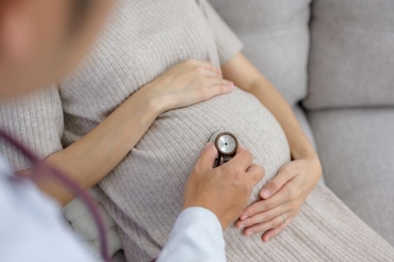 Un médecin en train d'ausculter une femme enceinte