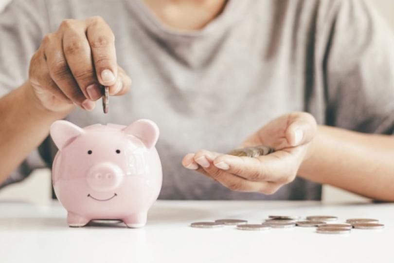 Une personne mettant des pièces de monnaie dans une tirelire cochon