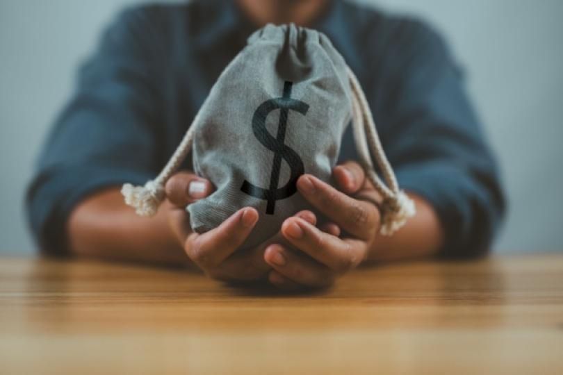 Une personne tenant dans ses mains un sac de dollars