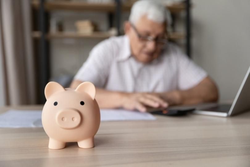 Une tirelire cochon avec un senior en arrière-plan