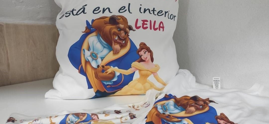 Una almohada blanca con una imagen de Bella y la Bestia.