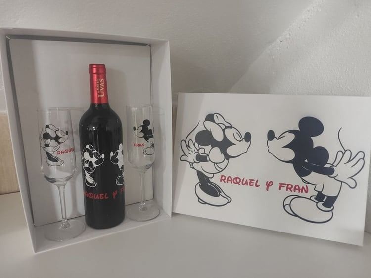Una botella de vino y dos copas de vino con Mickey Mouse en ellas.