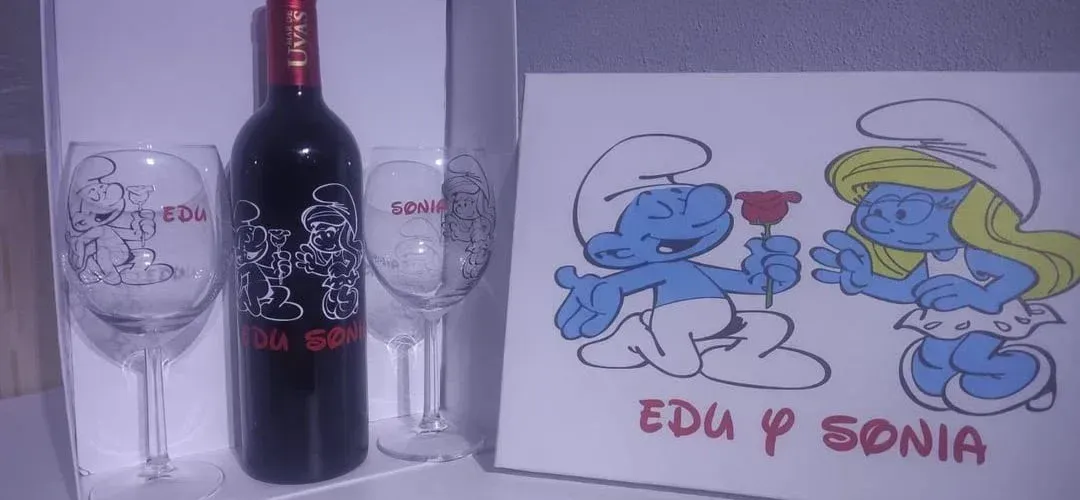 Una botella de vino y dos copas de vino con pitufos en ellas