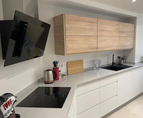 Una cocina con gabinetes blancos y un horno negro.
