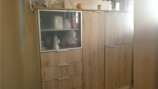 Un armario de madera con cajones y una puerta de cristal en una habitación.