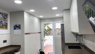 Una cocina con gabinetes blancos, un fregadero, un refrigerador y una puerta corrediza de vidrio.