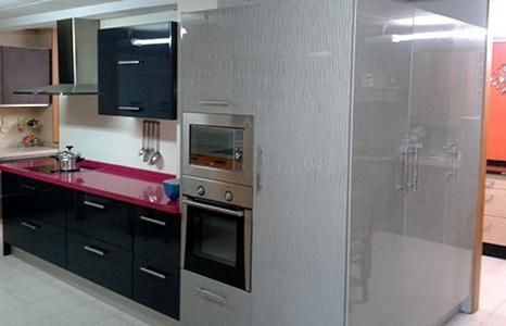 Una cocina con gabinetes negros, electrodomésticos de acero inoxidable y una encimera roja.