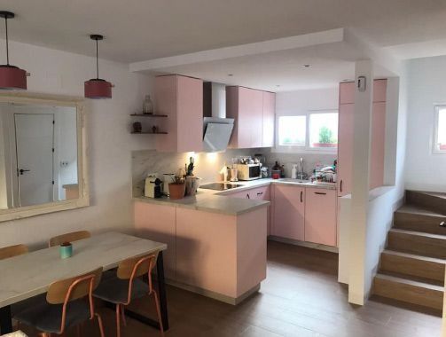 Una cocina con gabinetes rosas y una mesa y sillas.