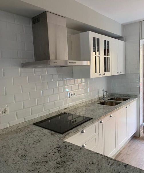 Una cocina con gabinetes blancos y un horno de estufa.