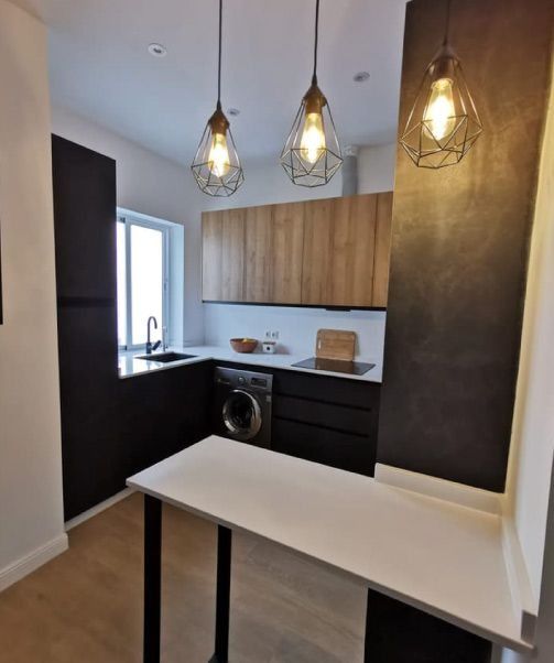 Una cocina con gabinetes negros y una encimera blanca.