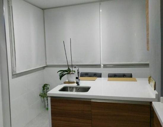 Una cocina con fregadero y una ventana con persianas.