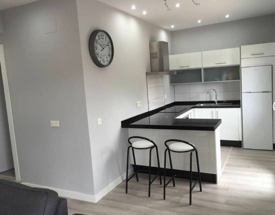 Una cocina con dos taburetes y un reloj en la pared.