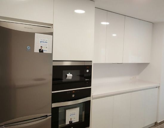 Una cocina con gabinetes blancos y electrodomésticos de acero inoxidable.