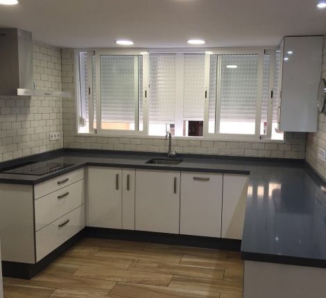 Una cocina con gabinetes blancos y encimeras negras.