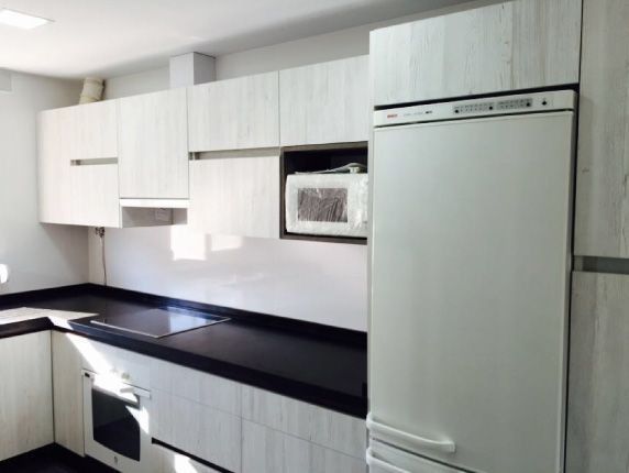 Una cocina con gabinetes blancos y encimeras negras.